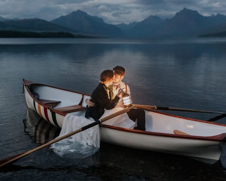 couple sitting in rowboat on mountainous lake at dusk