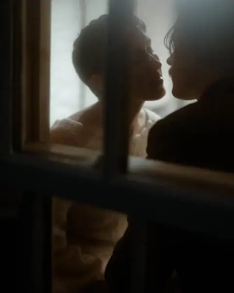 Intimate elopement momenet between the groom and bride trought the window.