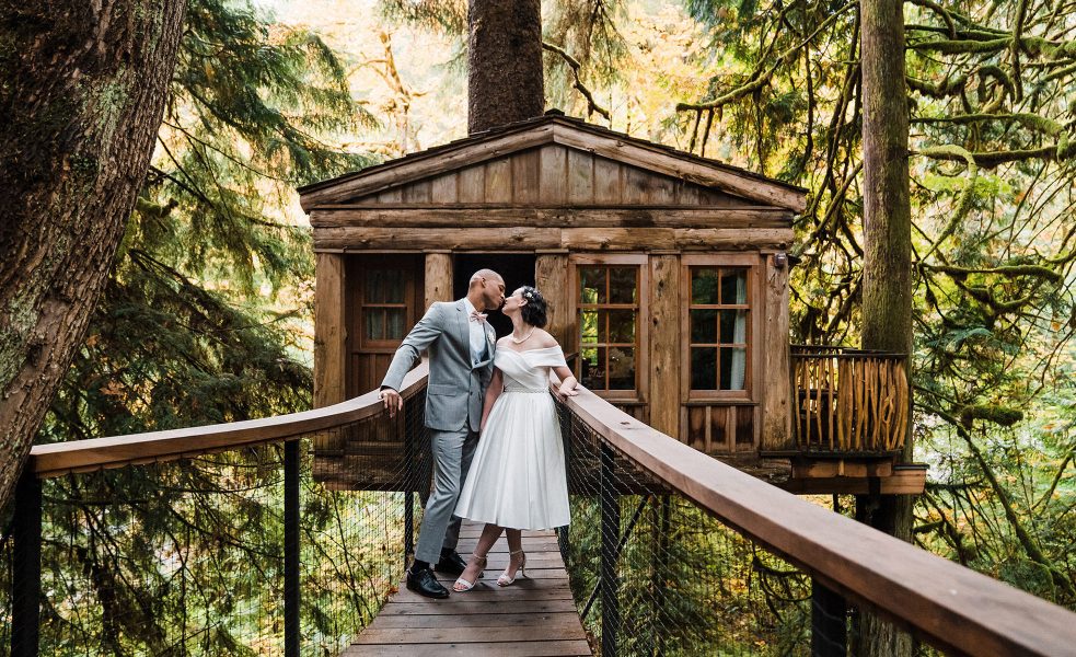 A couple kisses in front of a treehouse at Washington's Treehouse Point photographed by Amy Galbraith