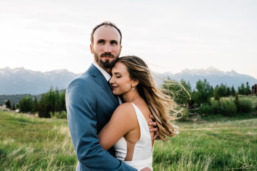 A bride and groom embrace as they take photos at sunset just outside of Grand Teton National Park