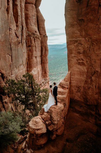 Couple on a steep rock ledge during their Sedona Arizona wedding