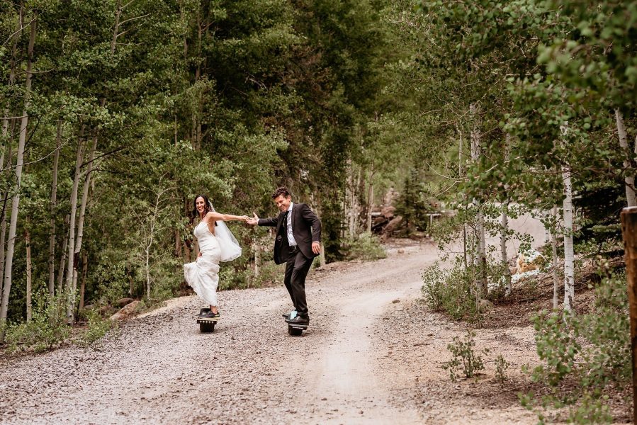 Couple one-wheeling down a dirt road during their Colorado elopement in Lake City