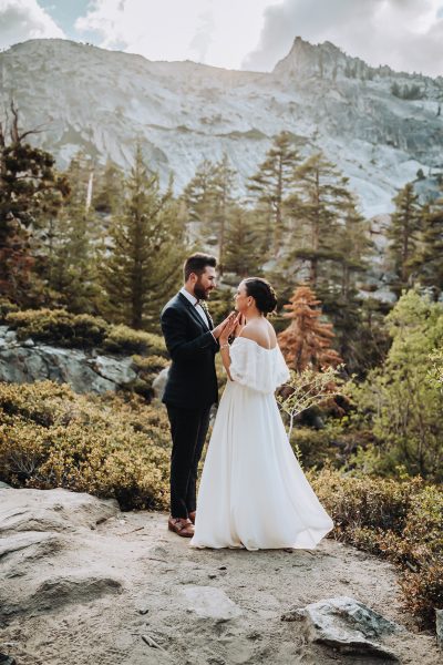 A wedding couple dancing on a rock overlooking a mountain backdrop in Lake Tahoe for their elopement day