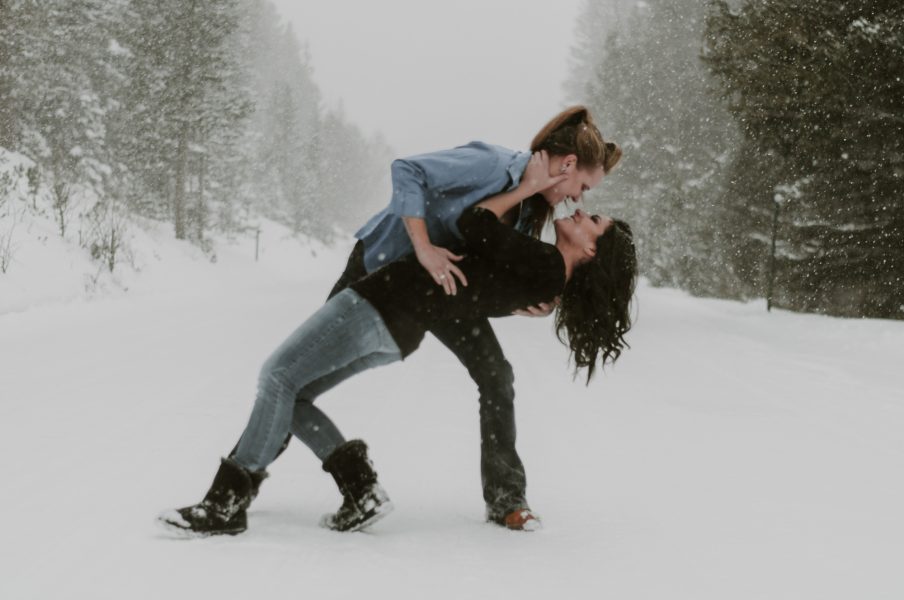 lesbian couples kissing in the snow in the mountains