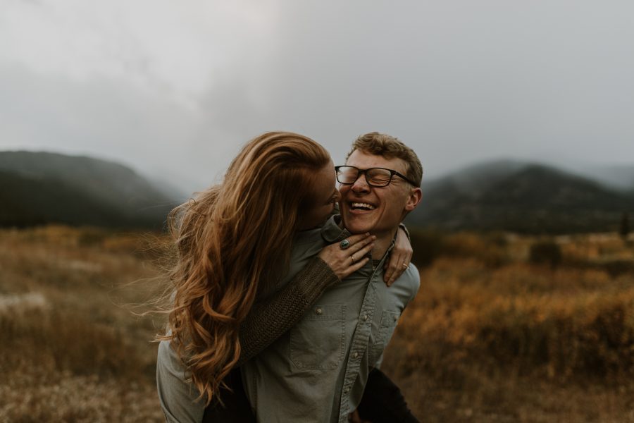 couple piggy backing and kissing in moody mountain scene