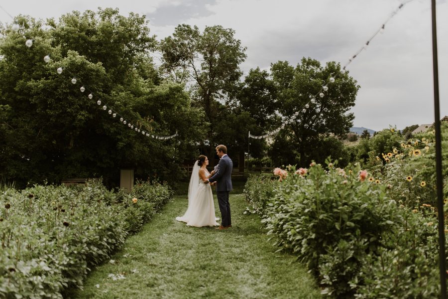 couple in wedding attire reading letter on flower farm