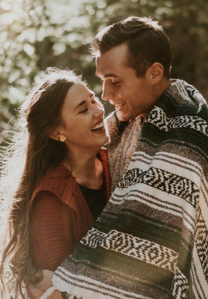 couple bathed in sunlight embracing under a blanket
