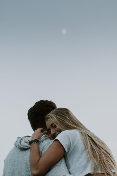 couples cuddling at blue hour with the moon above