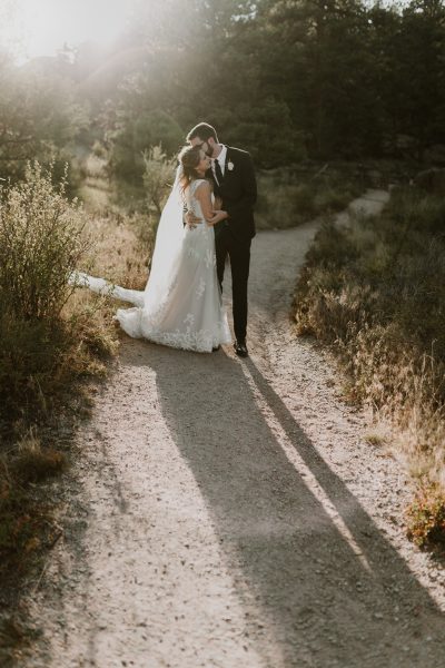 couple in wedding attire kissing on mountain trail
