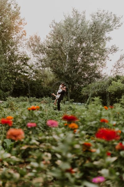groom holding bride in kiss in flower garden