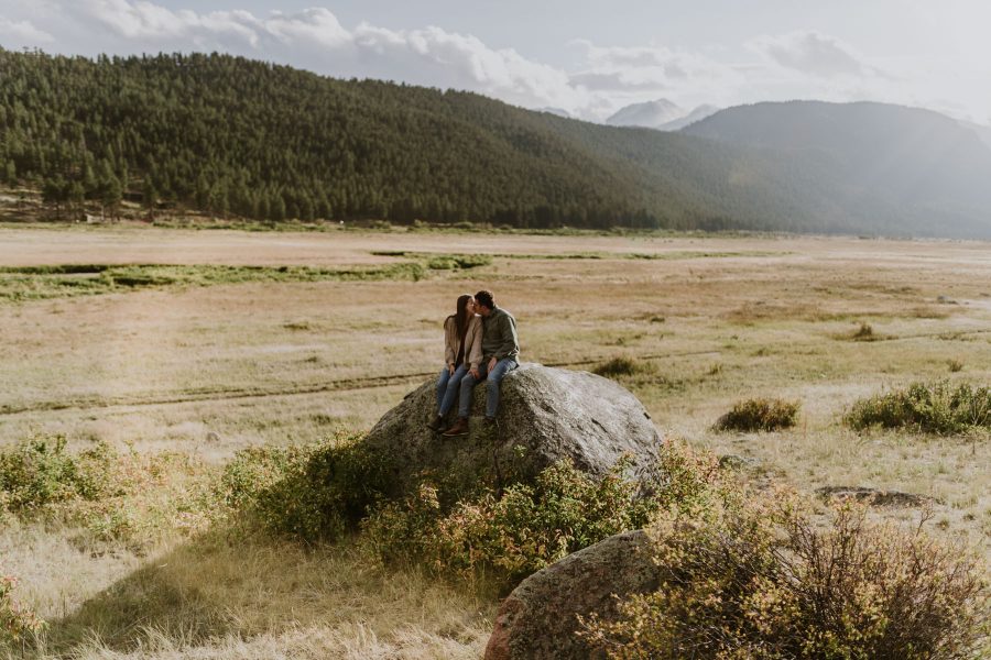 couple sitting on rock in a valley in the mountains