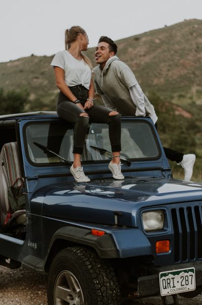 couples sitting on blue jeep acting goofy