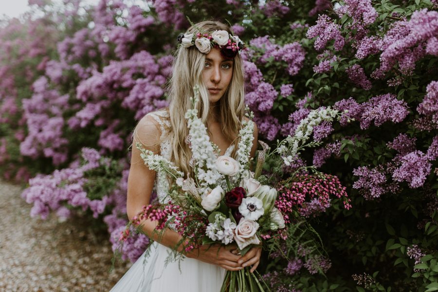 boho bride holding bouquet among lilacs