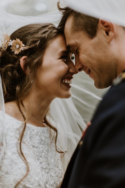 couple standing with foreheads touching under veil