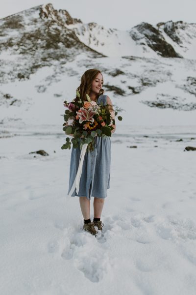 bride holding bouquet on top of snowy mountain