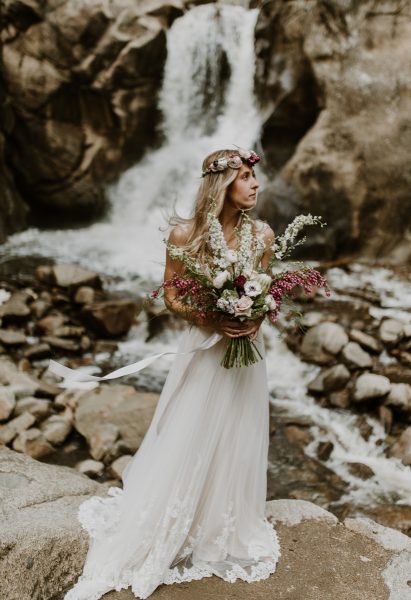 boho bride standing in front of a waterfall