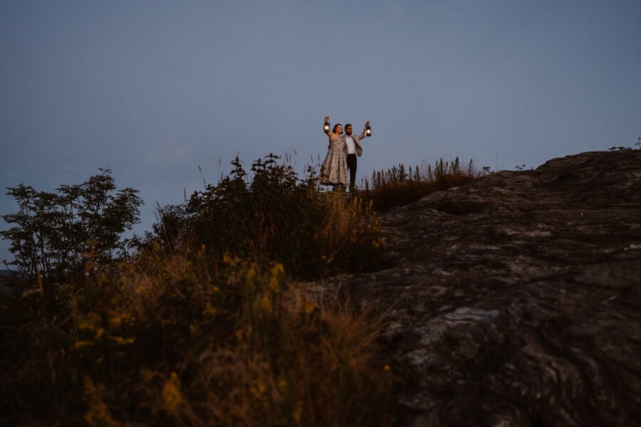 Couple standing on mountaintop with lanterns in Pisgah National Forest