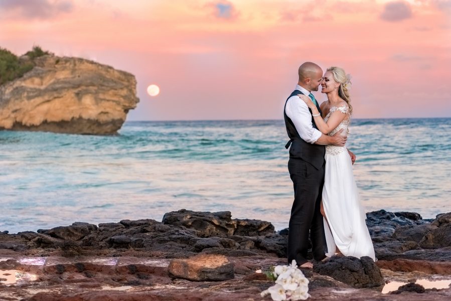 Bride and groom in front of a full moon pastel sunset on a beach in Kauai, Hawaii