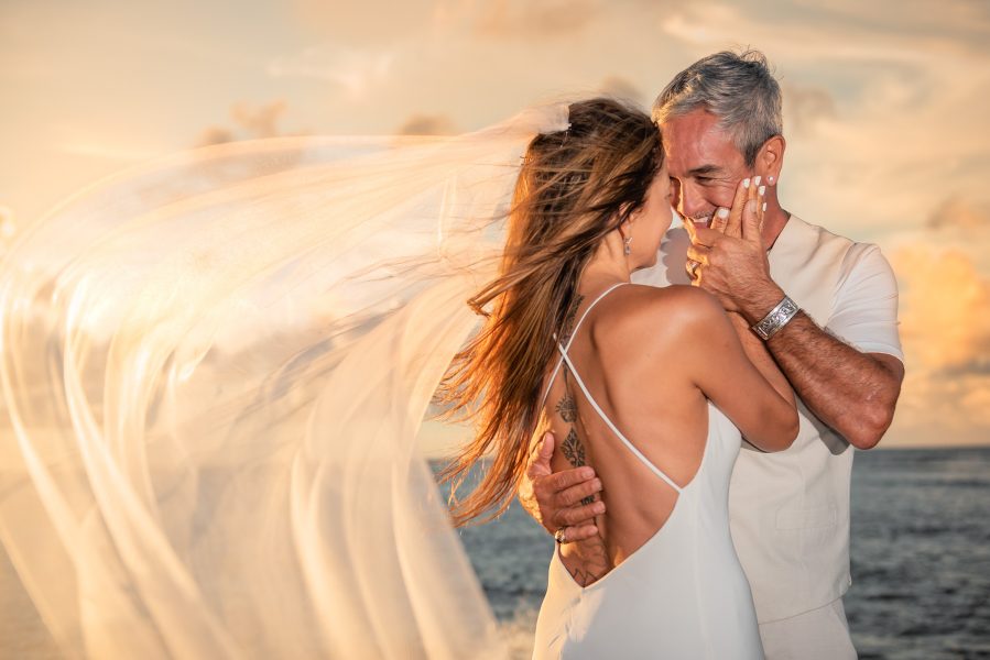 Groom kisses his bride at sunset in Kauai, Hawaii
