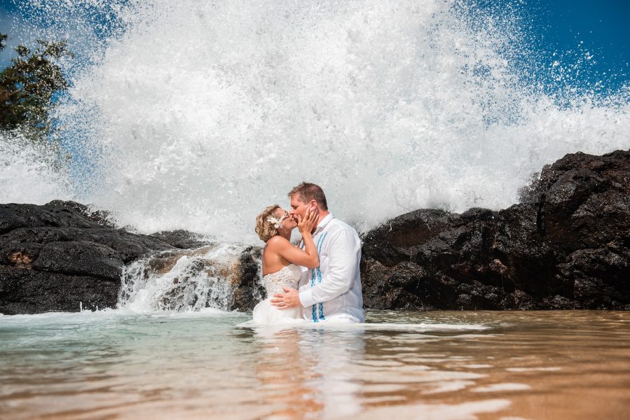 Bride and groom trash the dress in a tide pool on a secluded beach in Kauai, Hawaii