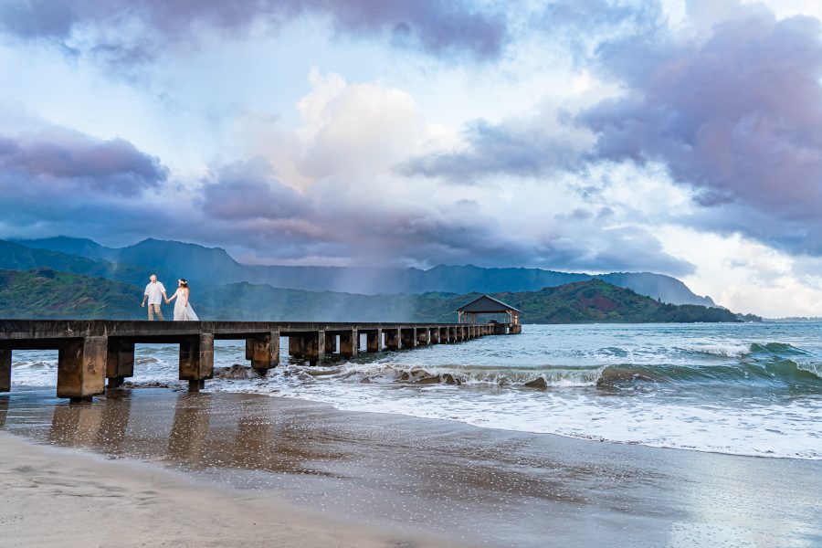 Bride and groom walking on the Hanalei Pier in Kauai, Hawaii