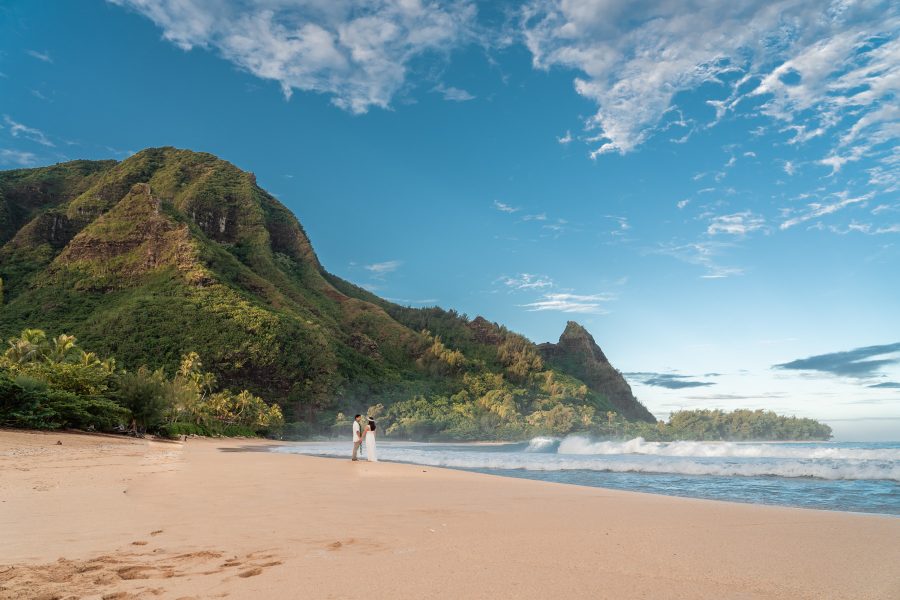 Bride and groom walking on a lush green Mountain View beach in Kauai, Hawaii