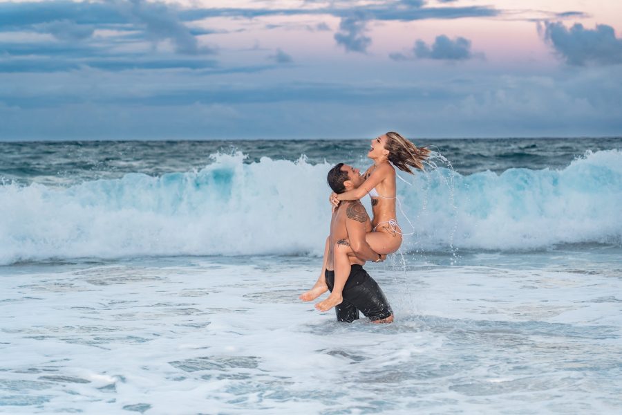 Couple playing in the waves on their Kauai, Hawaii honeymoon