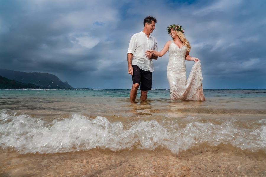 Bride and groom playing in the water in their wedding dress and suit in Kauai, Hawaii