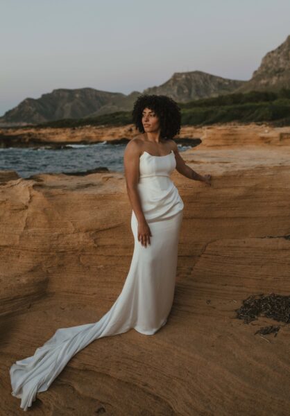 A bride stands near the sea after her elopement ceremony in Mallorca.