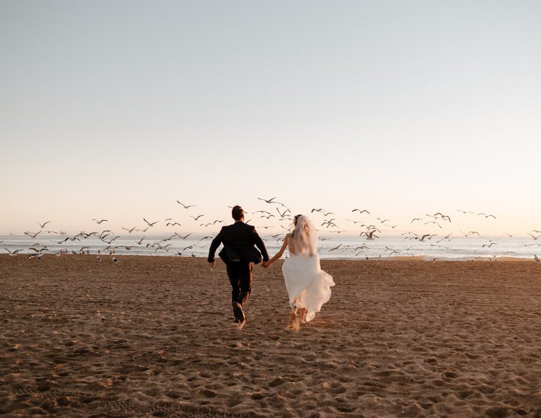 A couple runs through a flock of birds during their elopement in San Diego, CA.