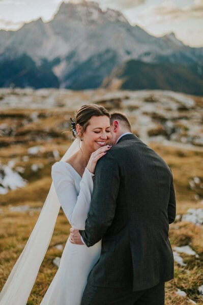 Beautiful bride and groom hugging in front of a gorgeous mountain backdrop in Italian Dolomites