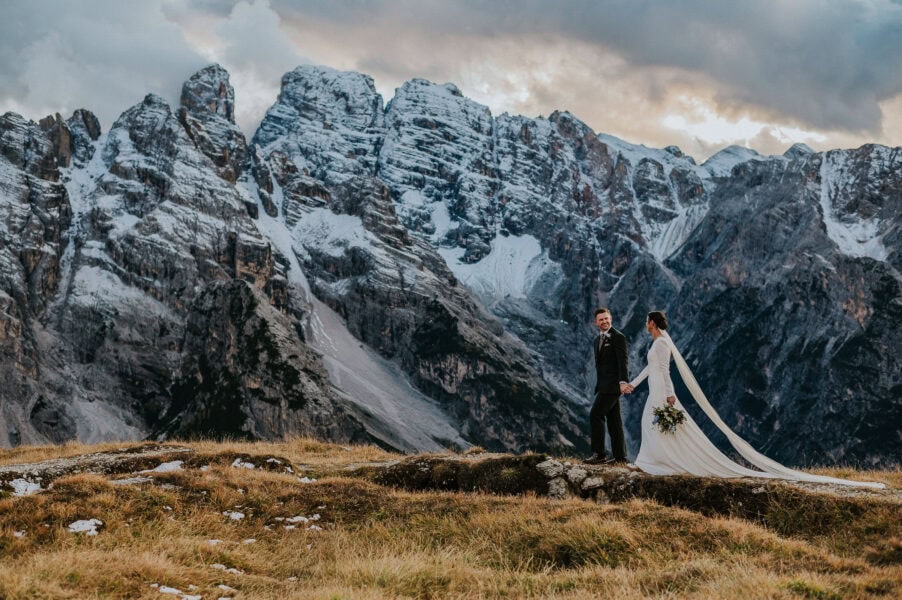 Bridal couple walking among gorgeous landscapes in Italian Dolomites while the sun is setting