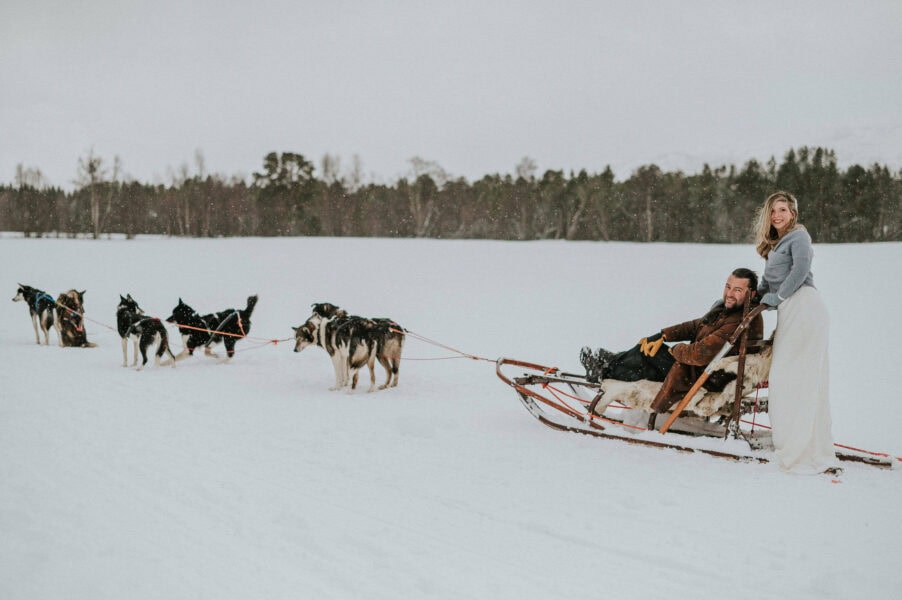 Bride and groom dogsledding on the day of their winter elopement in Alta Norway