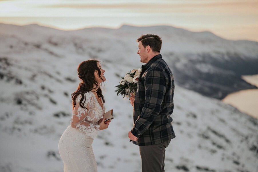 Bride and groom on a snow capped mountains in Alta Norway - reading their elopement vows to each other
