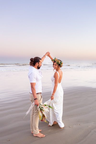 A bride and groom dance on the beach in Galveston Texas during sunset.