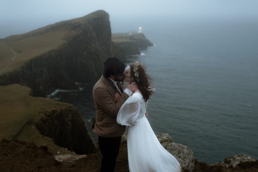 Bride and groom kiss on a clifftop on the Isle of Skye in Scotland
