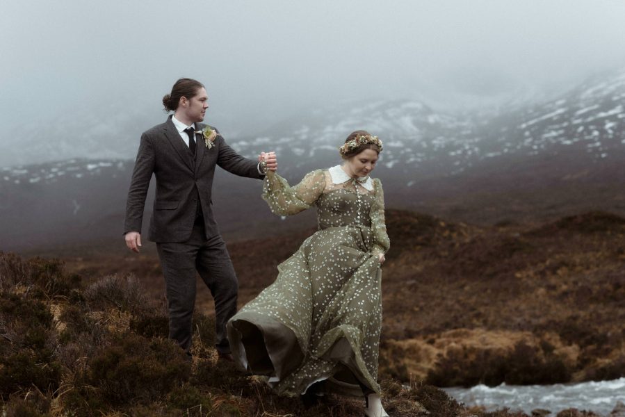 Bride and groom walking hand-in-hand in the Scottish mountains on the Isle of Skye