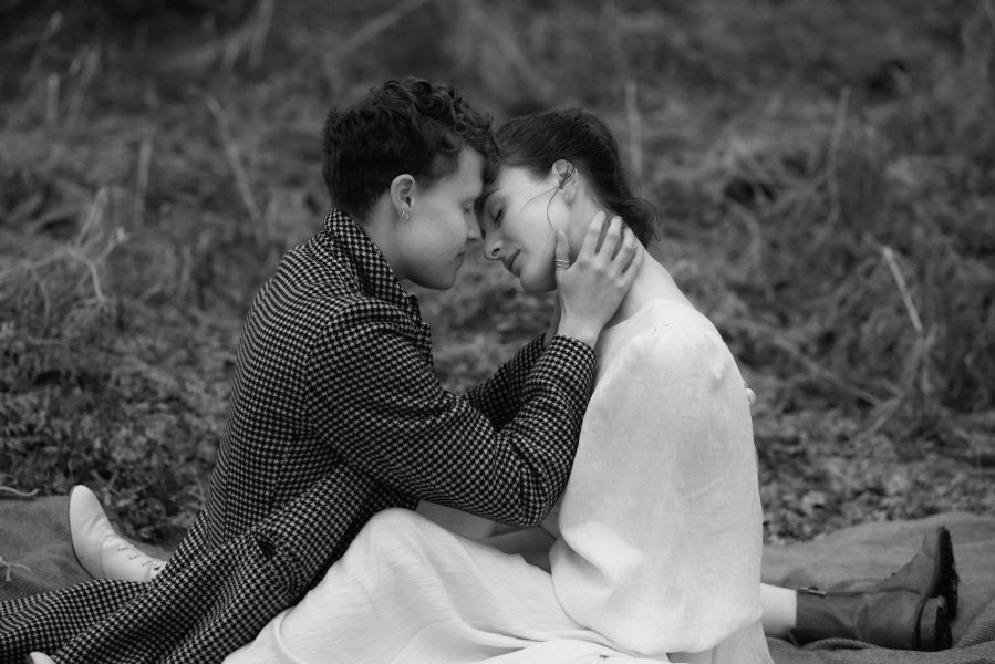 Two brides sitting on the ground and embracing