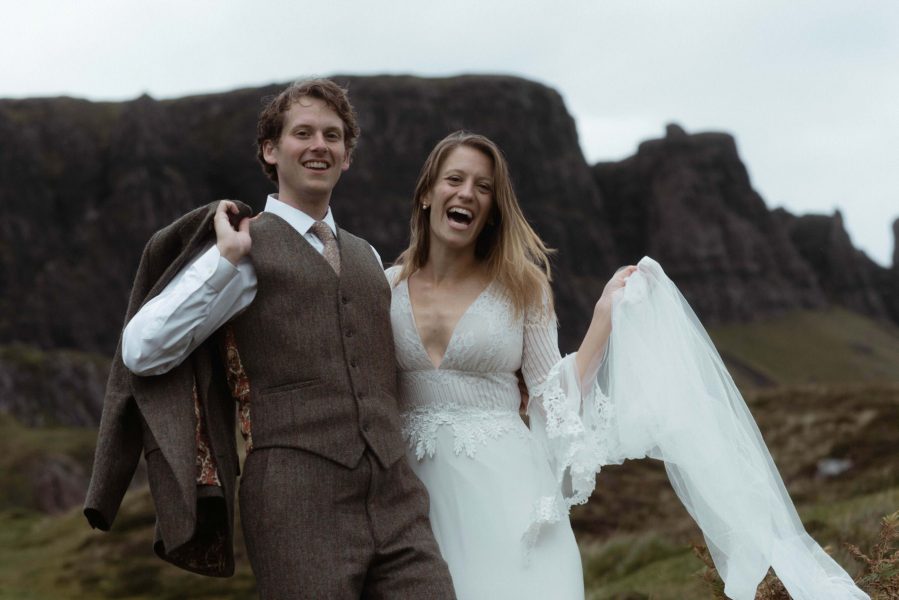 Bride and groom laughing and smiling against a Scottish mountain backdrop