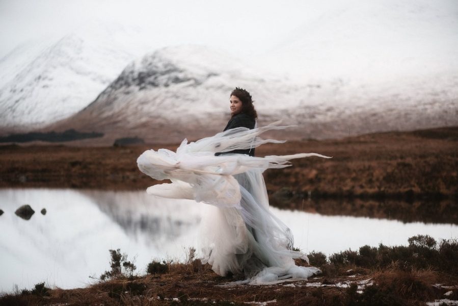 Bride swirling her wedding dress in front of a snowy mountain backdrop in Glencoe, Scotland