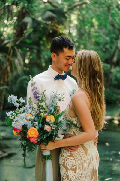 bride and groom stands in front of a spring