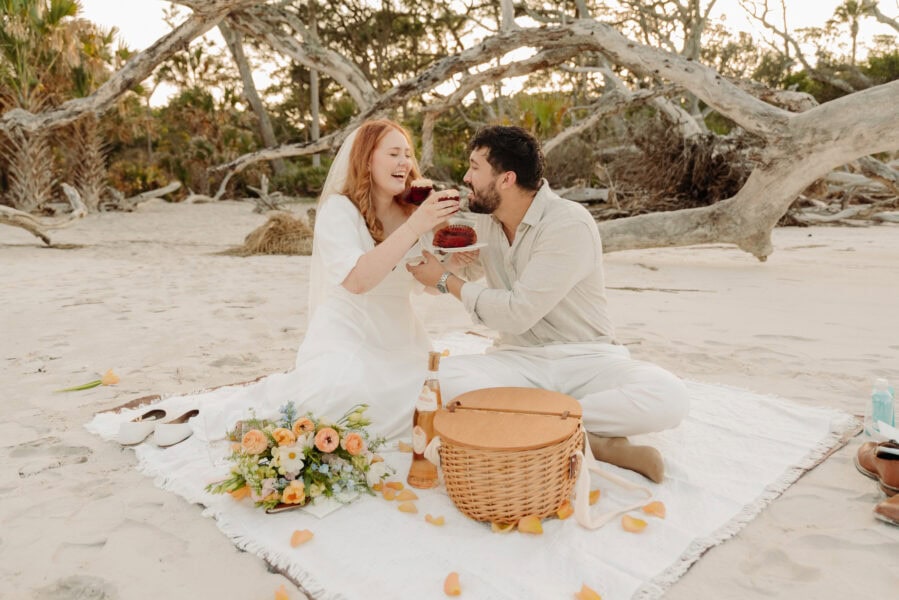 bride and groom enjoy a picnic together during their elopement on the beach