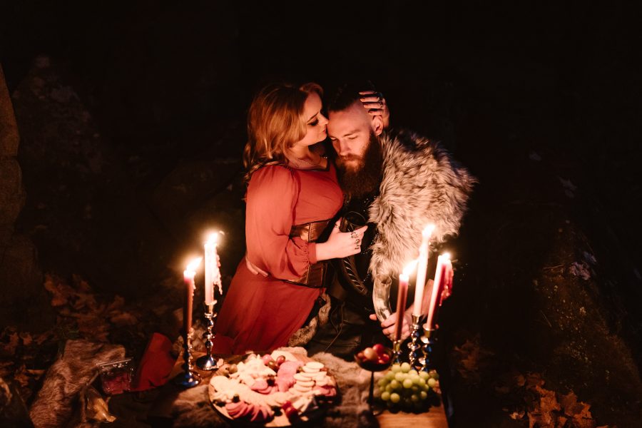 A couple dressed up like vikings celebrating their elopement at night with candles and a feast.