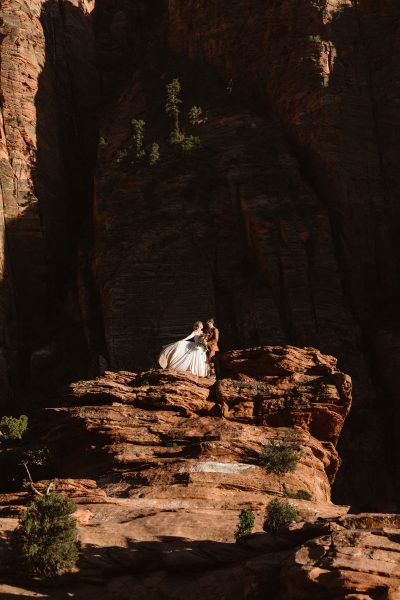 A couple standing on a large boulder in Zion National Park, UT.