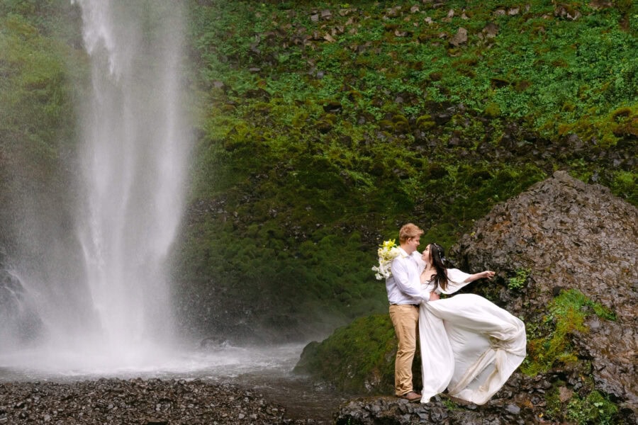 Bride twirling in her wedding dress beneath the cascading waterfalls at Latourell Falls in the Pacific Northwest.