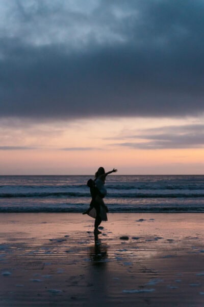 Groom twirling the bride under the starlit sky at Indian Beach, with waves crashing gently in the background, creating a dreamy and romantic scene.