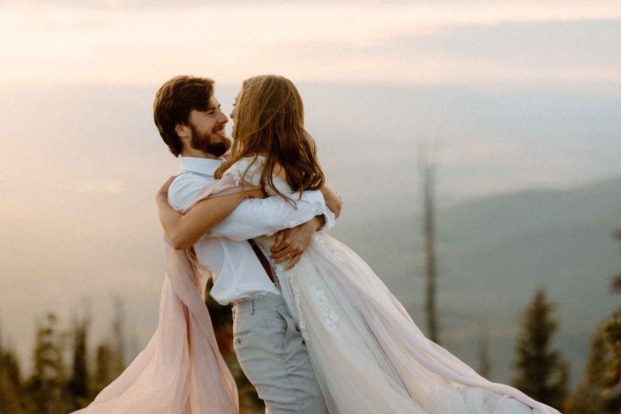 couple twirling in wedding attire in the mountains