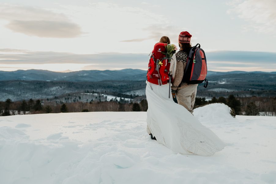 couple standing on top of a mountain after skiing for their Vermont winter elopement