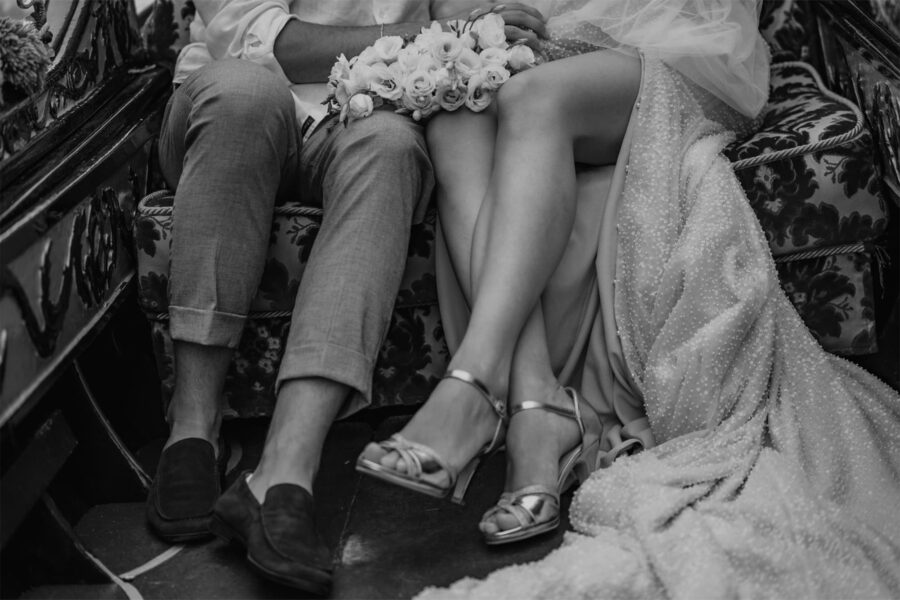 detail photos of bride and groom legs and feet in gondola on the Venice, Canals