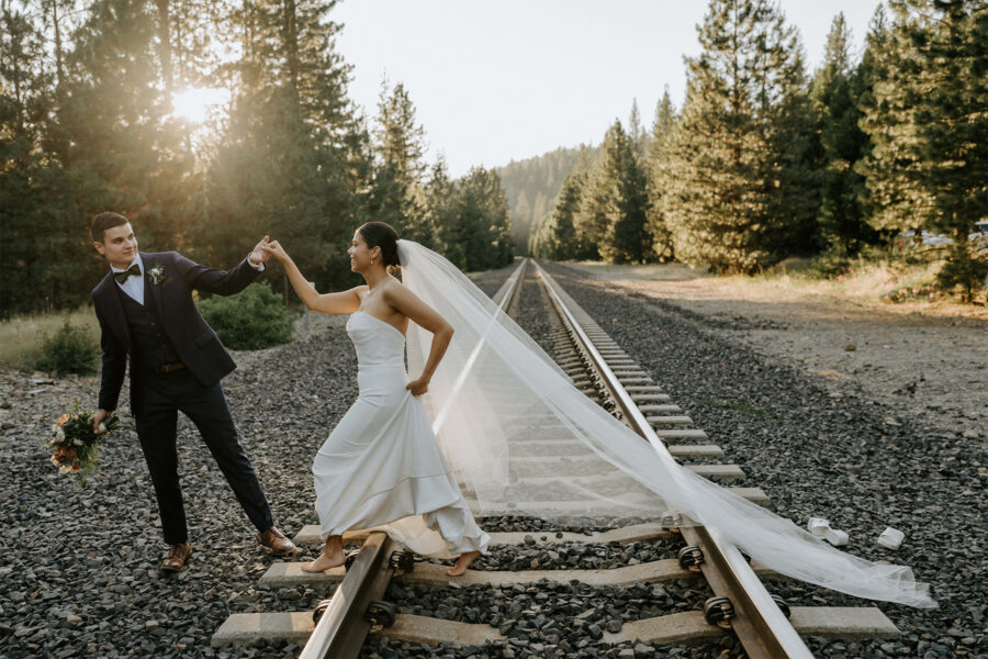couple adventuring over rail tracks on their elopement